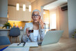 © Dragana Gordic - Senior Woman Multitasking with Coffee and Smartphone at Home Office