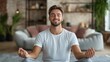 © fotofabrika - Young man practicing mindfulness meditation in a cozy, modern living room with soft lighting and comfortable furnishings during the afternoon