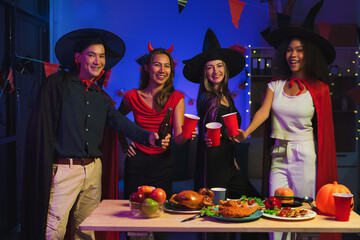 Wall Mural - Dinner and group of people celebrating together at Halloween party. Friends are happy and celebrating with food, wine and friendship of love and cheers of champagne at the event.