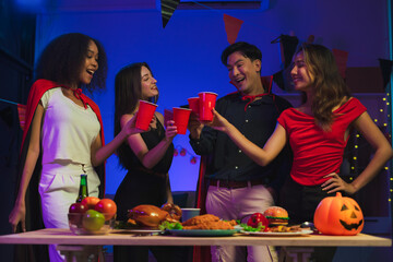 Wall Mural - Dinner and group of people celebrating together at Halloween party. Friends are happy and celebrating with food, wine and friendship of love and cheers of champagne at the event.