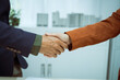 © NanSan - A businessman shakes hands with a customer in the sales office after agreeing to sign a contract to buy and sell a condo building. They discuss loans and real estate investment opportunities.