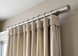 © Curie - The sleek wall-mounted track stretches along the length of the wall, curtains flowing effortlessly from its curved shape, filtering in warm sunlight and soft breezes.