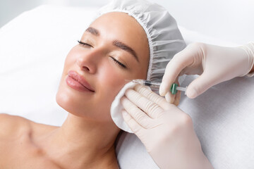 beautiful relaxed woman at beautician cabinet receiving anti wrinkle injections on cheekbones, lying