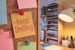 © Bruno Mazzetti - Colorful sticky note saying 'Keep Smiling' pinned on a corkboard in a cozy office.