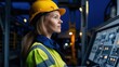 © angel_nt - A woman in a hard hat and reflective work attire is focused on operating machinery controls in a control room, ensuring smooth operations at a manufacturing facility at night