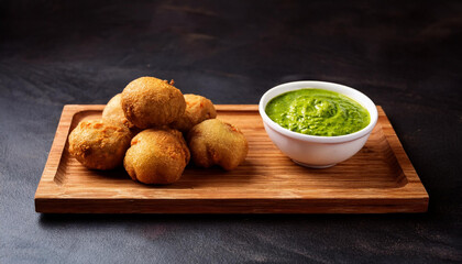 Wall Mural - Delicious Indian snack Vada with green chatni on wooden board 