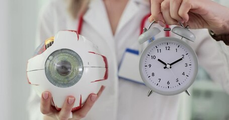 Wall Mural - Ophthalmologist holds a model of eye and alarm clock in clinic