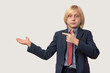 © somemeans - Portrait of a young boy in a business suit pointing at something with his finger on a white background