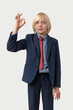 © somemeans - Young Caucasian boy in blue suit showing ok sign and looking at camera. Isolated on white background.