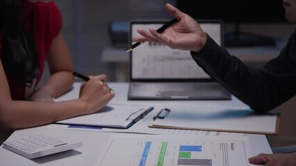 Poster - Business partners shaking hands after signing contract in office at night. They are working together using laptop computer and financial document