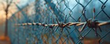 Close-up of barbed wire on a fence, representing security, restriction, or boundaries, with a blurred background in soft focus.