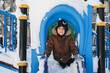© alexkoral - happy child boy is playing on a playground on a slide outside in winter.