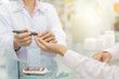© jokekung - Pharmacist performing blood glucose test on patient in pharmacy. Close-up of hands with glucometer. Healthcare professional providing diabetes screening service. Keep blood exam to diabetic screening.