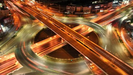 Wall Mural - Expressway, Beautiful top view time-lapse of car traffic at roundabout lane and buildings, Urban cityscape concept or abstract of advanced innovation, financial technology, energy power