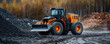 © khonkangrua - A large orange and black heavy construction loader moving coal at a mining or construction site, with a forest background.