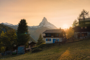 Wall Mural - Sunset over Matterhorn mountain with wooden chalet on hill in rural scene at Switzerland