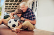 © Marko Geber - Grandfather playing soccer with grandson on patio