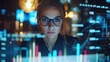 © dee-nesia - A female business professional is working on a laptop in an office, surrounded by digital graphs and charts