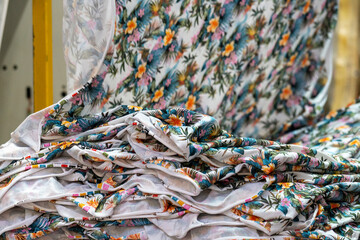 A pile of fabric with colorful flower designs in a textile manufacturer in close up view.