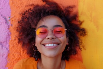 A joyful young woman laughs against a vibrant mural background on a sunny day