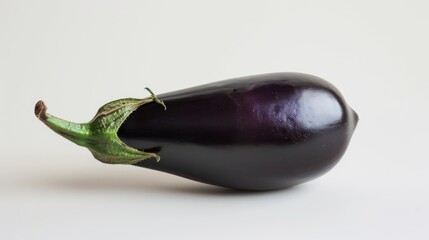 Wall Mural - A single eggplant sits on a white surface, providing a vibrant pop of color