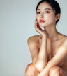 © Sandra Chia - Fashion commercial advertisement. Radiant porcelain glowing skin asian chinese woman posing with hand on face for facial skincare spa aesthetic ad. copy text space