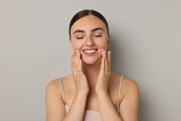 Poster - Face massage. Beautiful young woman with healthy skin on grey background