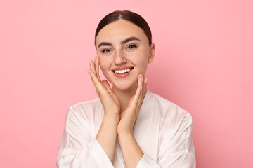 Wall Mural - Face massage. Beautiful young woman with healthy skin on pink background