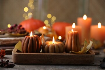 Wall Mural - Burning candles in shape of pumpkins and autumn decor on wooden table