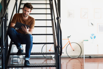 Poster - Man, office and tablet in staircase for creative idea, research and project as interior designer. Business, male employee and startup on website or online for communication, networking and connection