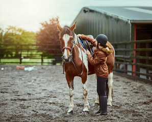 Horse, girl and adjust saddle at farm for race, sport and training at countryside ranch. Animal, equestrian and prepare seat for riding with pet for safety, care and protection with teenager outdoor