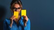 © K-MookPan - A young woman wearing glasses holds yellow notes, showcasing ideas and creativity against a dark background.