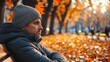 © Tetiana - Sad man wearing beanie sitting on bench in autumn park