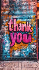 A colorful thank you mural stands out against a textured brick wall, showcasing vibrant graffiti art in a busy urban area