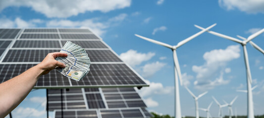 Poster - businessman holds dollars as savings after installing solar panels or wind power plants