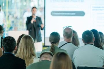 Wall Mural - Business professional giving presentation to engaged audience in a modern conference setting. Focus on communication and learning.