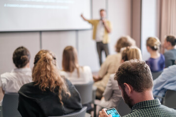 Wall Mural - Audience attentively listens to speaker during business presentation in modern conference room. Focus is on people engaged in learning and discussion.