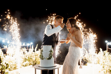 newlyweds happily cut and taste the wedding cake