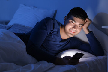 Poster - Young man using mobile phone in bed at night