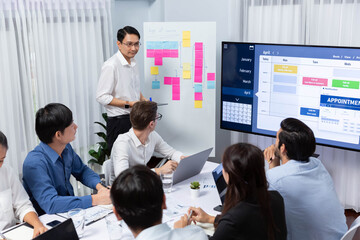 Poster - Project manager communicate and collaborate with team using project management software display on monitor, tracking progress of project task and making schedule plan at meeting table. Prudent