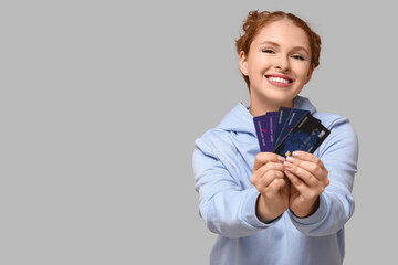 Wall Mural - Beautiful young woman with credit cards on grey background