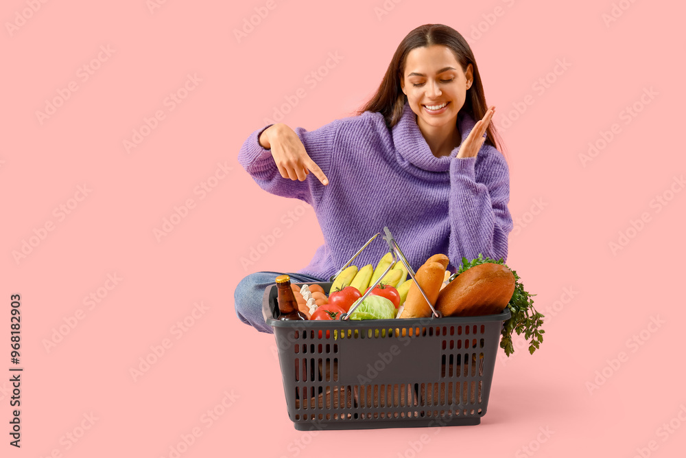Young woman with shopping basket on pink background