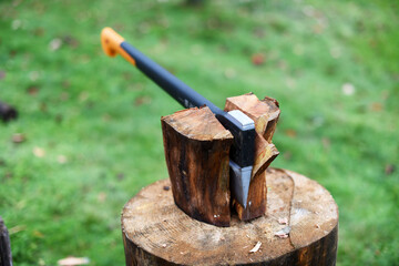 Axe is stuck in a piece of log wood used for chopping other wood. Winter preparation. Europe, Czechia.