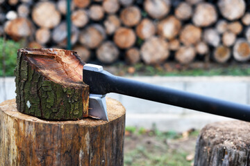 Axe is stuck in a piece of log wood used for chopping other wood. Winter preparation. Europe, Czechia.