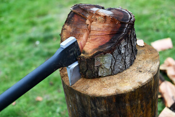 Axe is stuck in a piece of log wood used for chopping other wood. Winter preparation. Europe, Czechia.