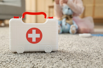 toy first aid kit and little girl on background