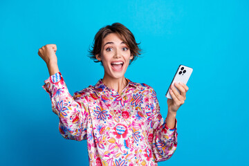 Sticker - Portrait of attractive overjoyed lady hold smart phone raise fist shout yes hooray isolated on blue color background