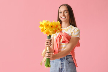 Wall Mural - Beautiful young happy woman with bouquet of beautiful narcissus on pink background