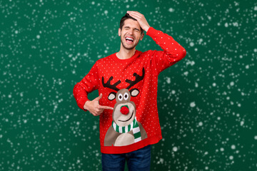 Poster - Photo portrait smiling man pointing at funny knitted sweater with reindeer laughing isolated green color background