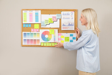 Poster - Mature woman near board with business plan on light wall